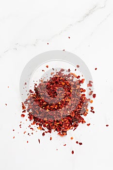 Crushed pimienta roja red pepper pile from top on white background. Heap of red pepper flakes, ground red chili pepper paprika photo