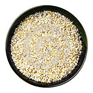 Crushed pot barley groats in round bowl isolated