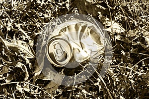 Crushed soda can lying in grass - in sepia tone
