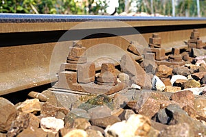 The crushed stones or ballast alongside the rail track hold the wooden cross ties in place, which in turn lock the i