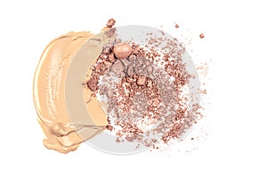Crushed texture of beige face powder and beige makeup smear of creamy foundation on isolated backgound