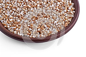 Crushed wheat or barley groats in a brown ceramic bowl isolated on a blue background