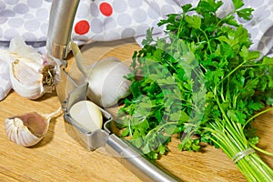 Crushing garlic to add to the dish. Whole and chopped garlic on a cutting Board made from natural oak. Fresh parsley.