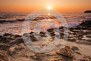 Crushing waves on jagged rocks during sunrise