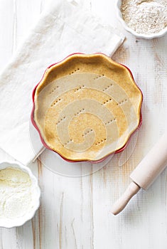 Crust on baking sheet , pots with wheat and bran flour and rolling pin on white wooden table