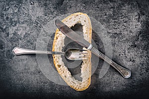 Crust of bread fork and knife on concrete board. Toned image