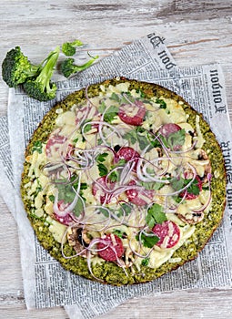 Crust Broccoli base low carbs keto pizza with salami, avocado on vintage newspapper. Top view photo