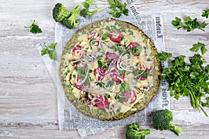 Crust Broccoli base low carbs keto pizza with salami, avocado on vintage newspapper. Top view