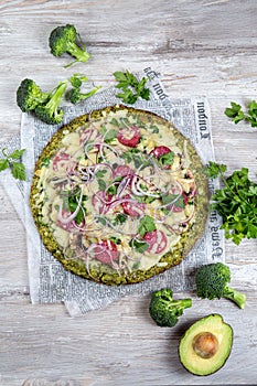 Crust Broccoli base low carbs keto pizza with salami, avocado on vintage newspapper. Top view