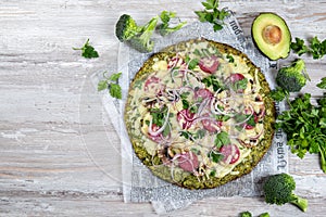 Crust Broccoli base low carbs keto pizza with salami, avocado on vintage newspapper. Top view photo