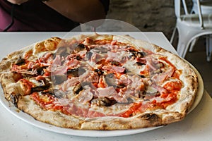 Crust ham and mushroom homemade pizza on table for lunch in Italian restaurant