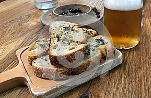 Crusty bread with herbs, olives and glass of beer on table