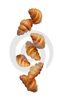 Crusty golden croissants falling on white background