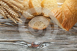 Crusty sliced bread rye ears on wooden surface