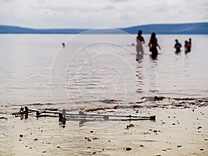 Crutches on a sand by water. People silhouettes in water, Selective focus. Concept healthcare, Water recovery procedure