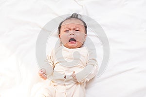 Crying and angry Newborn baby boy lying on white bed at home.Infant baby screaming very hungry or stomach pain.sick asian baby