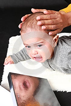 Crying baby boy with reflection in silver box