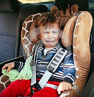 Crying baby boy in a safety car seat