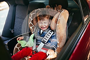 Crying baby boy in a safety car seat