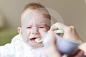 Crying baby eating porridge
