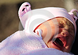 Crying baby in a hat and blanket on the street