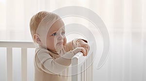 Crying baby portrait. Little infant tired and hungry, start crying standing in crib, looking aside at empty space