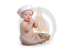 Crying Baby Sitting up Wearing Sailor Hat on White Background