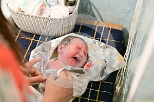 Crying baby when swaddling. A newborn 1 week old baby being examined by a pediatrician