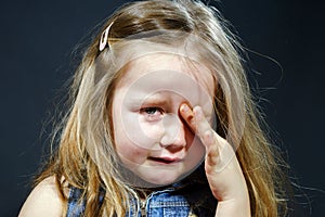 Crying blond little girl with focus on her tears