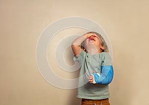 Crying boy with broken hand stand over wall