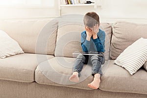 Crying boy with digital tablet at home