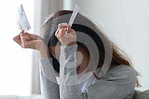Crying cheated woman hides face behind hands holding torn photo