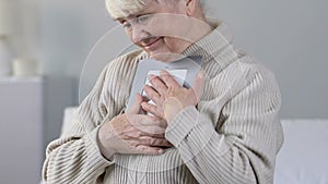 Crying elderly lady hugging photo in frame, thinking about gone person, memories