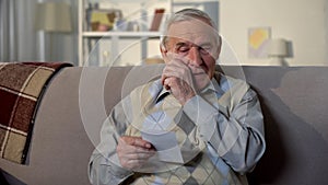 Crying elderly man looking at photo, remembering old lost friend, memories