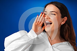 Crying emotional young woman screaming on blue studio background