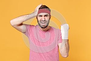 Crying fitness sporty guy sportsman in headband t-shirt in home gym isolated on yellow background. Workout sport