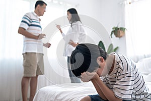 Crying illtle asian boy with his fighting parents in the background