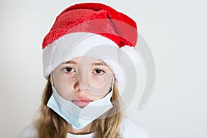 Crying kid with red santa claus hat and mask isolated on white background. Sad child face with surgical mask. Christmas covid 19