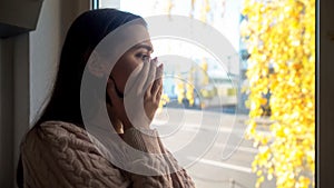 Crying lady looking through window, afraid of going outdoors agoraphobia disease photo