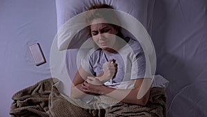 Crying lady lying in bed and holding positive test, unplanned pregnancy, topview