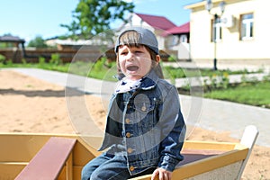 Crying little boy on playpit in summer