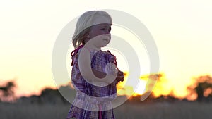 Crying little girl alone in the meadow. Child at sunset in the meadow.