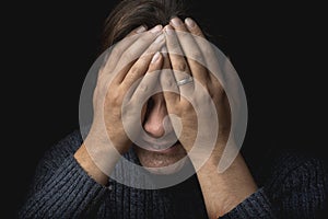 Crying man suffers and covers his face with hands. Depression, mental pain, tragedy, problems in life and grief concept