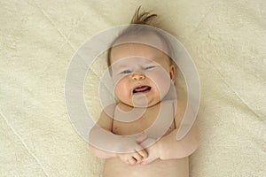 Crying newborn baby on bed, top view 4 month old baby portrait