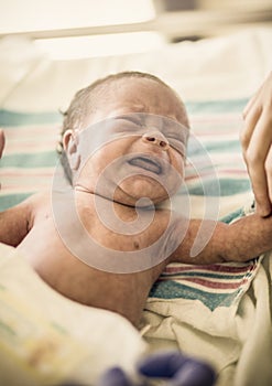 Crying Newborn infant baby boy in a hospital bed