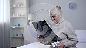 Crying old lady looking at brain x-ray in hospital, incurable disease, health