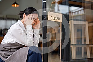A crying and upset Asian female coffee shop owner feeling sad to close her business