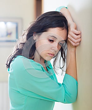 Crying woman standing near a wall