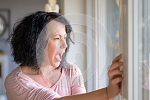 Crying woman standing at a window