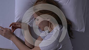 Crying woman using smartphone in bed, bad news from relatives, depression